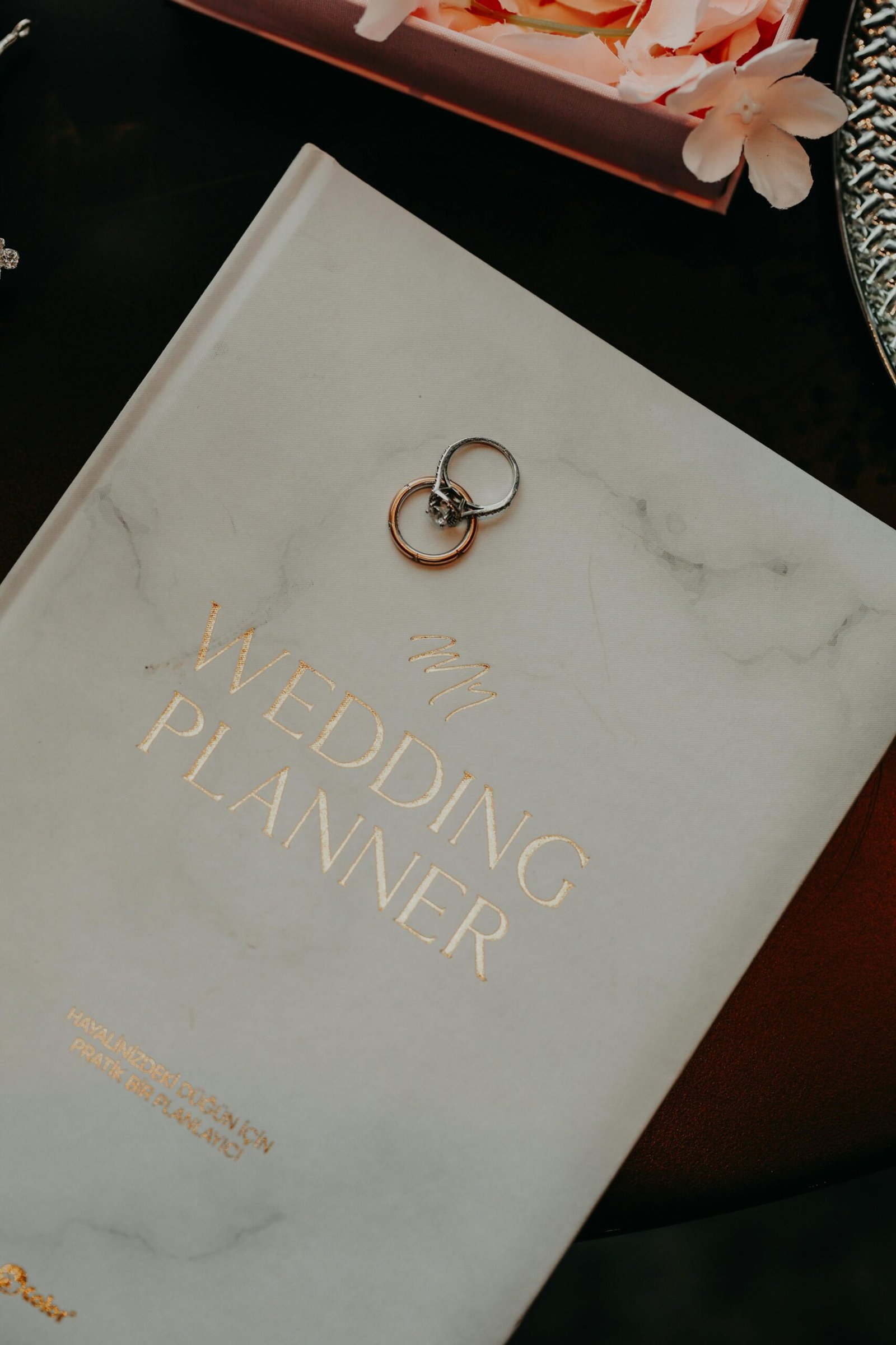 Close-up of a wedding planner book adorned with silver rings, symbolizing preparation and commitment.